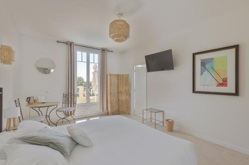 a white bedroom with a large bed and a table at La Garoupe-Gardiole Boutique Hotel in Antibes