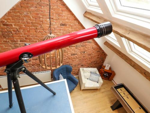 a red telescope in a room with a brick wall at Seahaven in Maryport