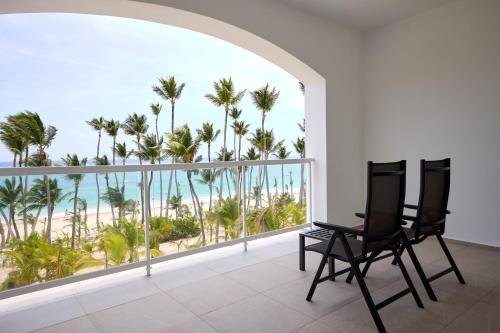 two chairs on a balcony with palm trees and the ocean at Riu Palace Bavaro - All Inclusive in Punta Cana