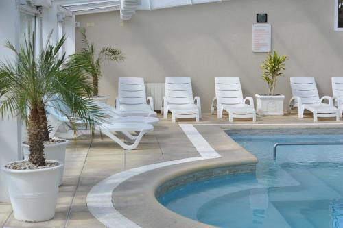 a group of white chairs and a swimming pool at Carilo Soleil By HS in Carilo