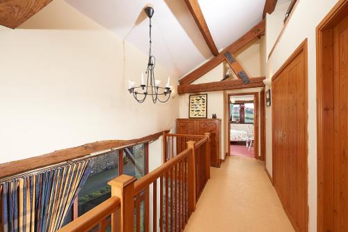 a hallway with wooden railings and a chandelier at Canny Brow Barn in Kendal