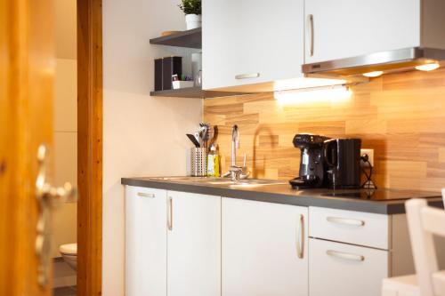 a kitchen with white cabinets and a sink at Apartmenthaus ROSE in Prutz