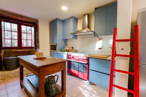 a kitchen with blue cabinets and a red ladder at Casa Justininho in Ponte de Lima