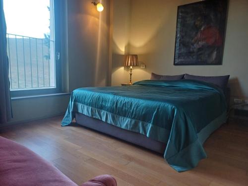 a bedroom with a bed with a blue blanket and a window at Agriturismo CASA DELLE VIOLE in Fornovo di Taro