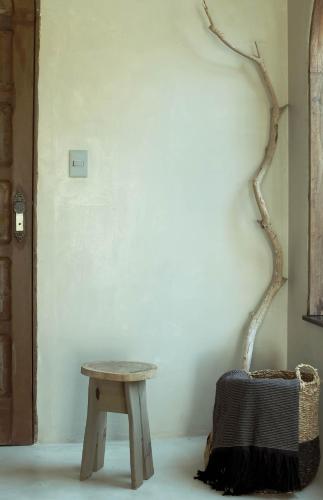 a wooden table and a stool next to a wall at Benção Hotel in Morro de São Paulo