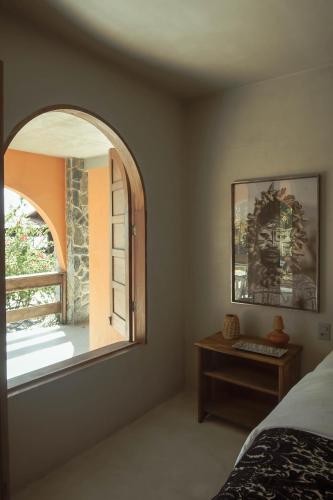 a bedroom with a window and a bed and a table at Benção Hotel in Morro de São Paulo