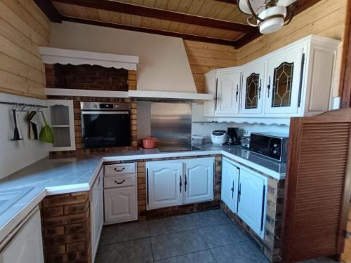 une cuisine avec des armoires blanches et des appareils électroménagers blancs dans l'établissement T3 Bagneres de Luchon , St Mamet, à Saint-Mamet