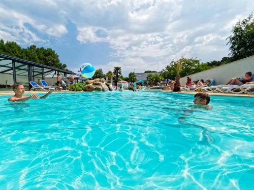 two children playing in the swimming pool at a resort at ZEcamping 4 étoiles animé parc aquatique pet friendly sauna in Saint-Lunaire