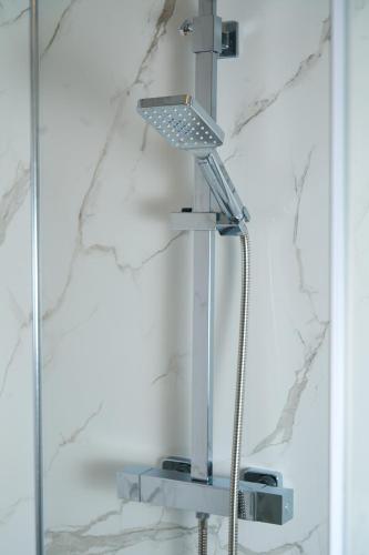 a shower in a bathroom with a shower head at Snooze Luxe House in Dallington