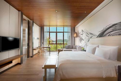 a hotel room with a large bed and a television at Yanqi Hotel, Managed by Kempinski in Huairou