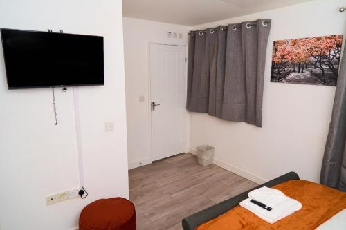 a living room with a flat screen tv on the wall at Snooze Luxe House in Dallington