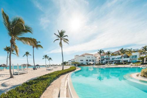 プンタ・カナにあるApartment with pool and ocean view in Punta Palmeraのヤシの木や建物が並ぶビーチのプール