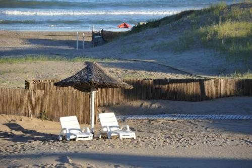 two chairs and an umbrella on a beach at Carilo Soleil By HS in Carilo