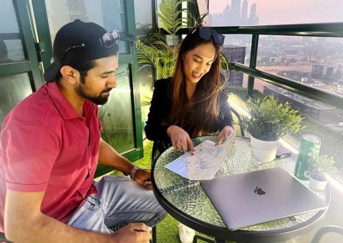 a man and a woman sitting at a table with a laptop at Beautiful Partition Room in Barsha heights in Dubai
