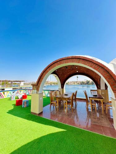 a patio with tables and chairs on the grass at Kaya Nubian House in Aswan