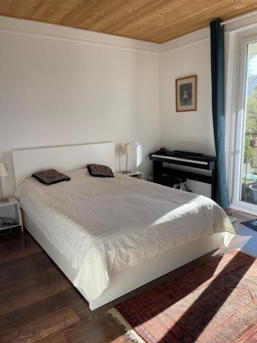 a white bedroom with a bed and a piano at sport et repos à Leysin CH in Leysin