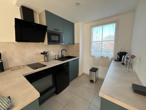 une cuisine avec des armoires bleues et un comptoir dans l'établissement Charmant T2 rénové avec balcon, proche plage et commerces, à Arès