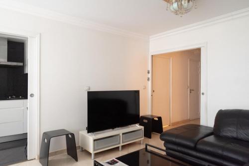 Il comprend un salon doté d'un canapé noir et d'une télévision à écran plat. dans l'établissement T3 apartment in the heart of La Villette, à Paris