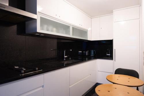 une cuisine avec des armoires blanches et des comptoirs noirs dans l'établissement T3 apartment in the heart of La Villette, à Paris