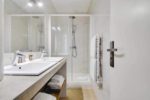 une salle de bain blanche avec un lavabo et une douche dans l'établissement Amazing apartment - 2BR 6P - Bastille, à Paris