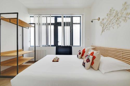 une chambre avec un grand lit blanc avec des oreillers dans l'établissement Amazing apartment - 2BR 6P - Bastille, à Paris