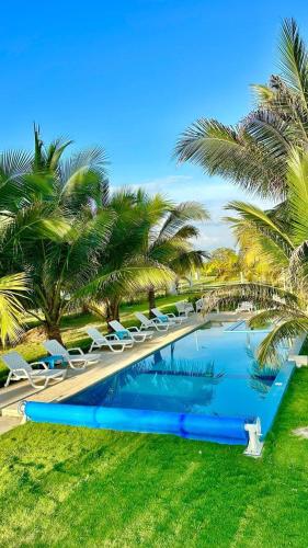 a swimming pool with lounge chairs and palm trees at PlayAkemi - Cojimies - Ecuador in Cojimíes