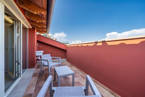 a balcony with chairs and a table on a red wall at Casina Rossa in Peccioli