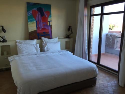a bedroom with a large white bed and a sliding glass door at Dar Carissa in Ala el Ma