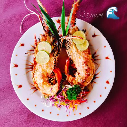 a plate of shrimp with vegetables on a purple table at French garden Pragash Beach Hotel in Trincomalee