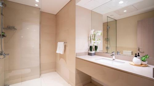 une salle de bain avec un lavabo, une douche et un miroir dans l'établissement Cozy 1br With Stunning Seaworld Views!, à Abu Dhabi