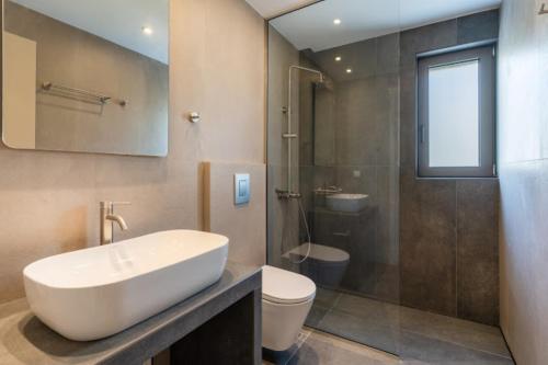 a bathroom with a sink and a toilet and a mirror at Dreta Suites in Chania Town