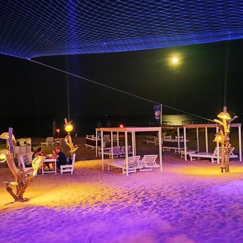 a group of people sitting at a table on the beach at night at French garden Pragash Beach Hotel in Trincomalee
