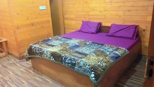 a bed in a room with purple sheets and pillows at Celebrations Place Farmhouse in Gurgaon