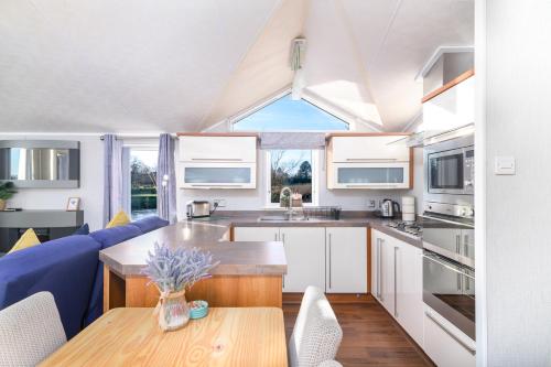 a kitchen with white cabinets and a wooden table at Primrose Valley Lakeside Lodge in Filey
