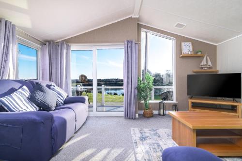 a living room with a blue couch and a tv at Primrose Valley Lakeside Lodge in Filey