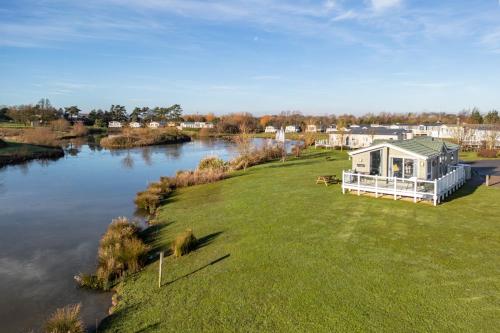 a house on a lawn next to a river at Primrose Valley Lakeside Lodge in Filey