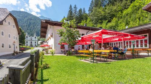 a group of people sitting at tables under red umbrellas at Gasthof Maria Kirchental in Sankt Martin bei Lofer