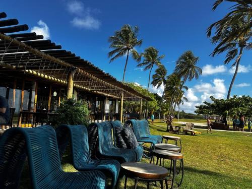 uma fila de cadeiras e mesas azuis e palmeiras em Angá Beach Hotel em São Miguel dos Milagres
