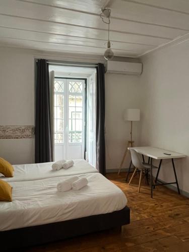 Un dormitorio con una cama y un escritorio y una ventana. en Alface Hall Hostel & Bar, en Lisboa