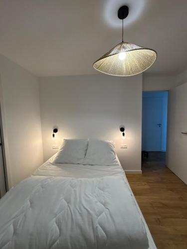 - une chambre avec un grand lit blanc et une lumière dans l'établissement Maison MADA SAINT CAST, à Saint-Cast-le-Guildo