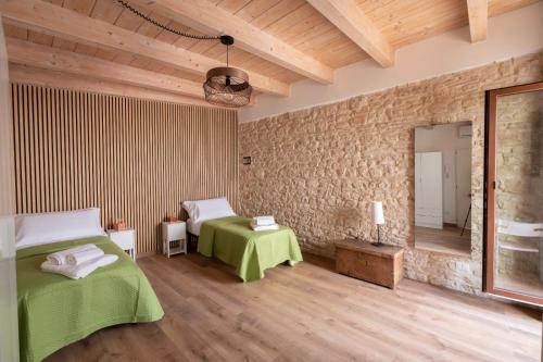 a bedroom with two beds and a stone wall at Palazzo Rizzi Dimora dei Templari in Bitetto