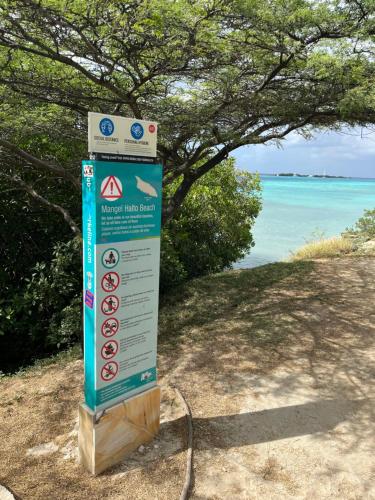 a sign on the side of a beach with the water at La Villas at Pos Chiquito Caribbean Paradise in Aruba in Savaneta