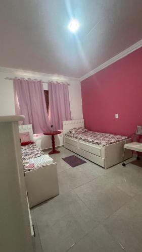 a room with two beds and a pink wall at Sitio Canto da Siriema in Domingos Martins