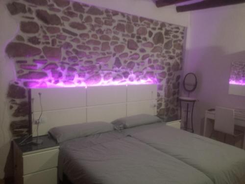 Un dormitorio con una cama con luces moradas. en Can Peiri, en Porrera