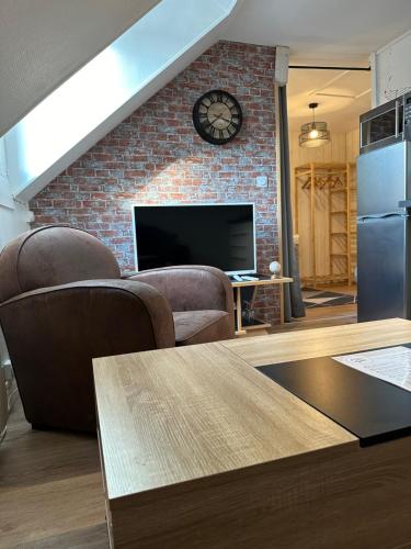 a living room with a clock on a brick wall at Le studio du square: beauval in Romorantin