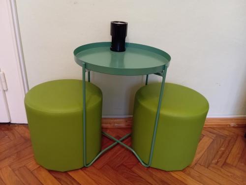 a table and two green stools with a vase on top at Green Cactus Rooms - unique and cozy house in Senta