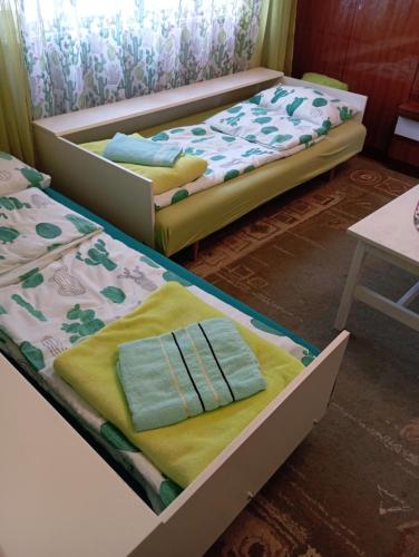 two beds in a room with towels on them at Green Cactus Rooms - unique and cozy house in Senta