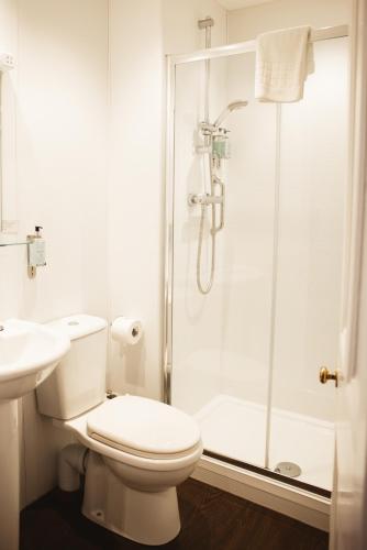 a white bathroom with a toilet and a shower at The Portree Hotel in Portree