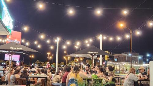 a crowd of people sitting at tables at a restaurant at night at Playa, centro y relax in Encarnación