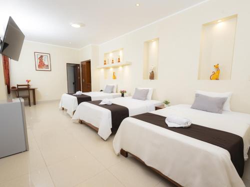 a group of four beds in a room at Hotel San Marino Tarapoto in Tarapoto